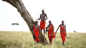 Maasai men standing beside a tree in the Maasai Mara, Kenya