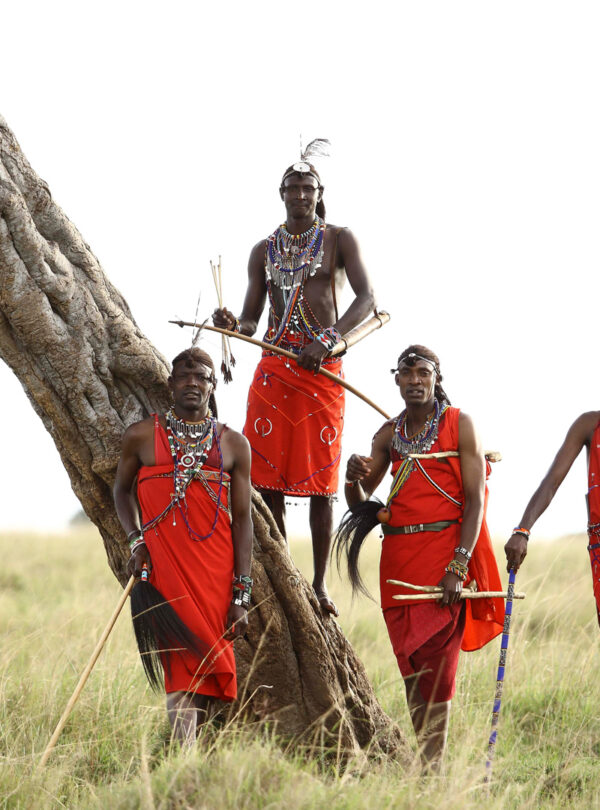 Maasai men standing beside a tree in the Maasai Mara, Kenya